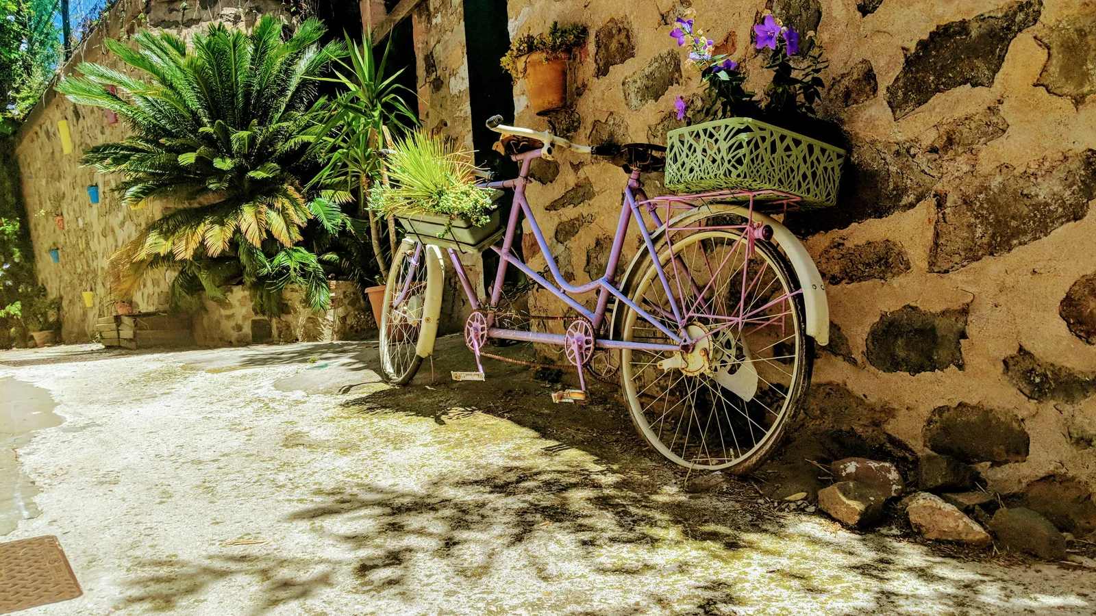 a purple bike parked next to a stone wall in France, illustrating enjoying France