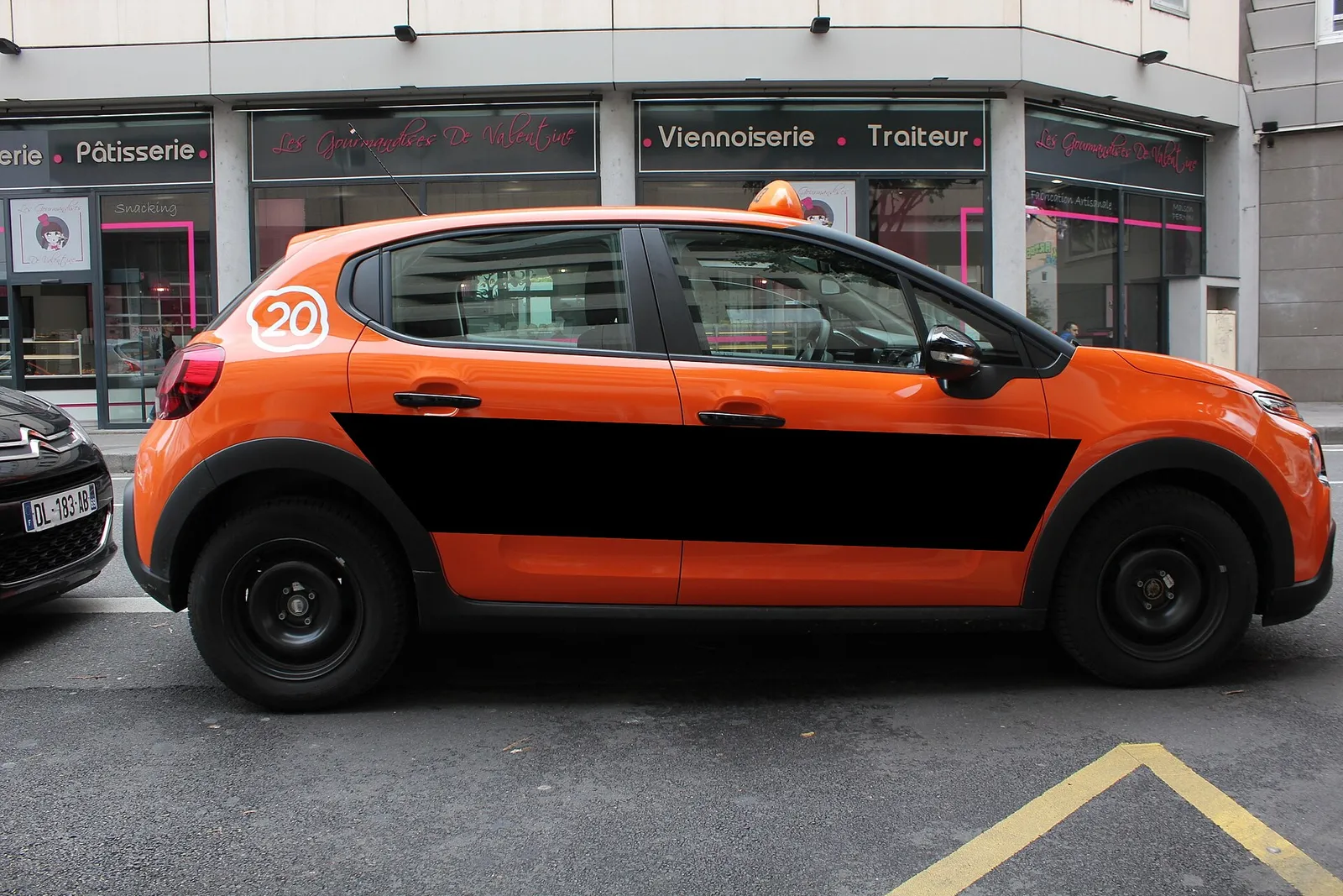 An orange driving school car parked in a Paris street