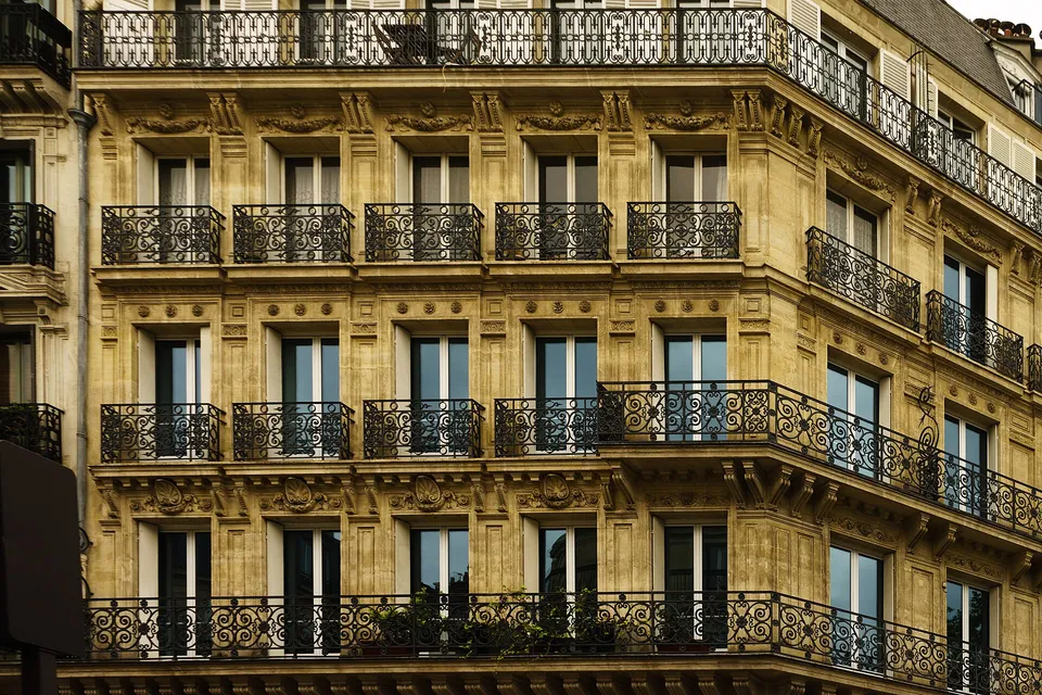 Haussmannian apartment building facade with wrought-iron balconies in Paris.