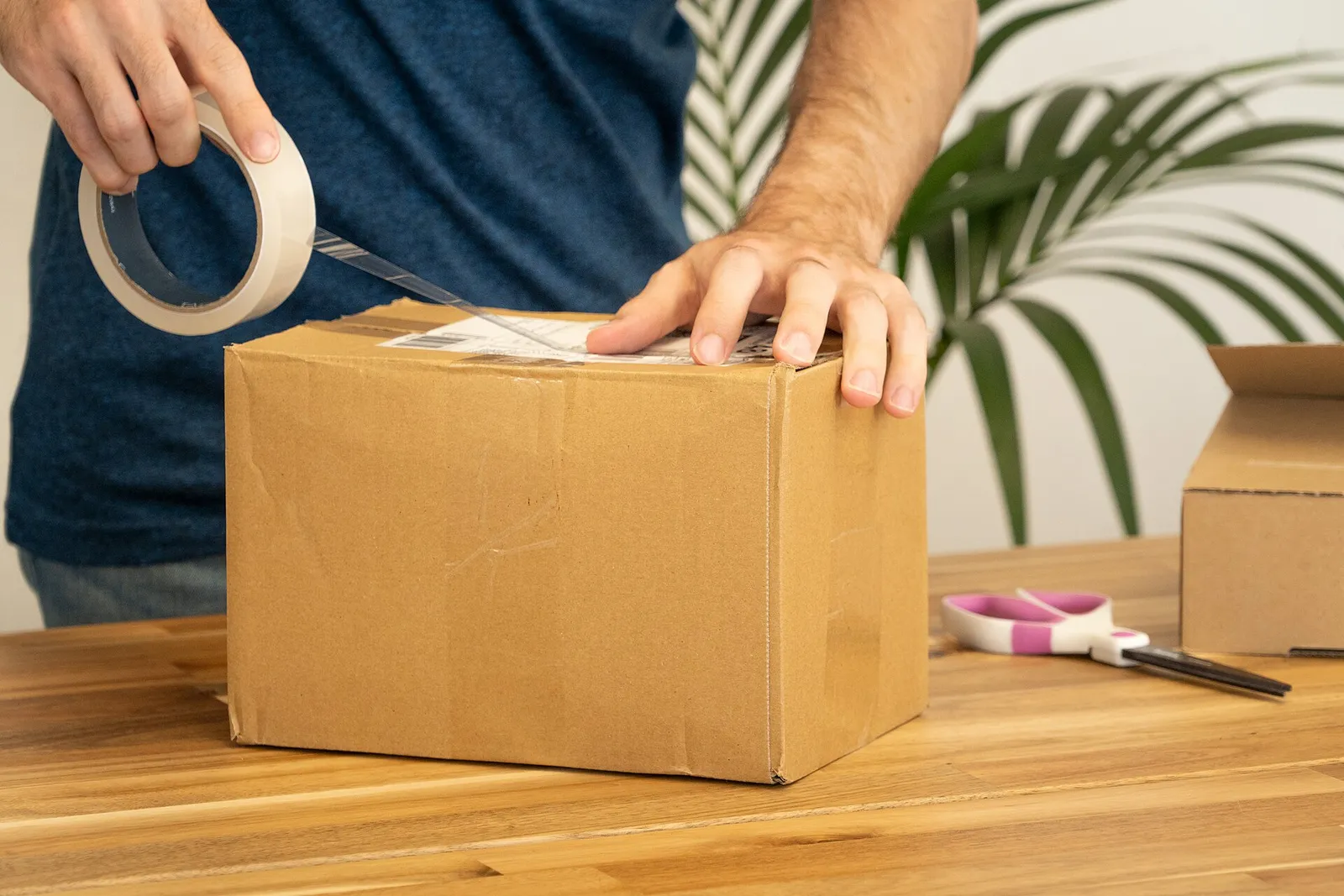 A man sticking a shipping label onto a cardboard parcel