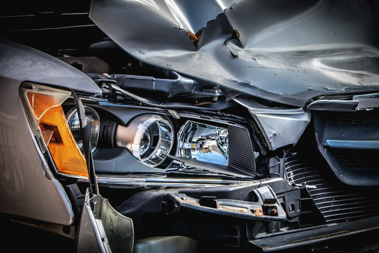 Close-up of a car with a crumpled hood and a broken headlight after a collision