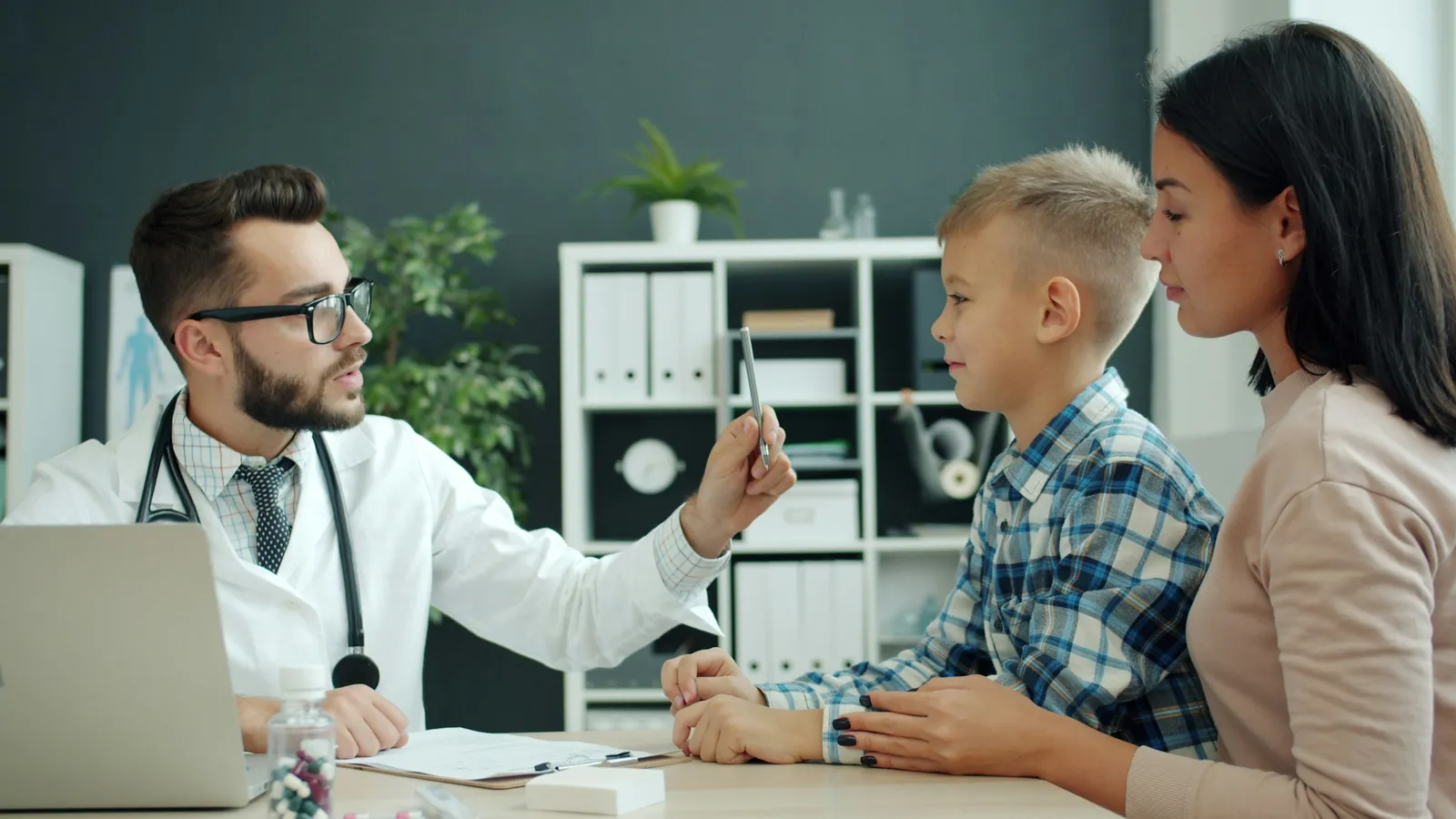 A doctor talking to a mother and her young son in a consulting room