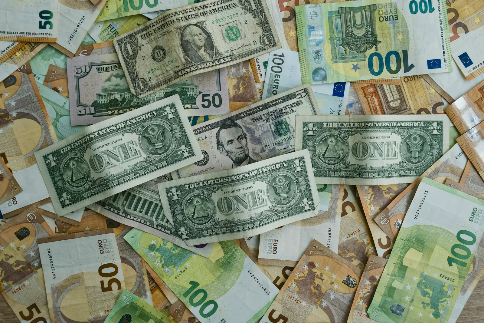 US dollar and euro banknotes of several values lie mixed together on a flat surface