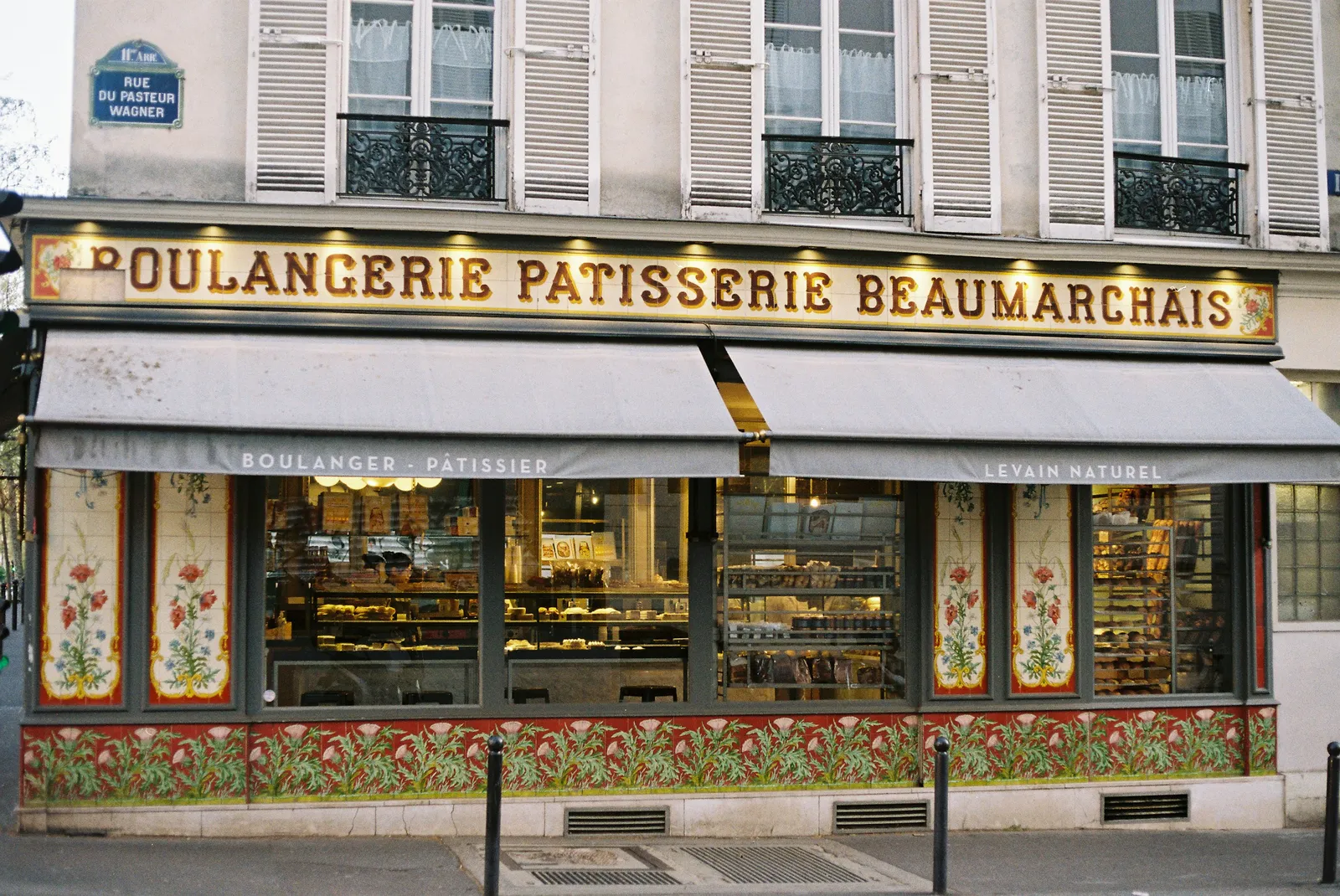 A Paris bakery and pastry shop storefront with painted floral panels under a gilded sign